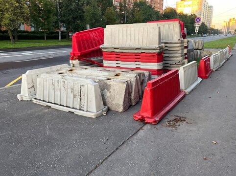 Red and white plastic traffic barriers stacked on urban roadside