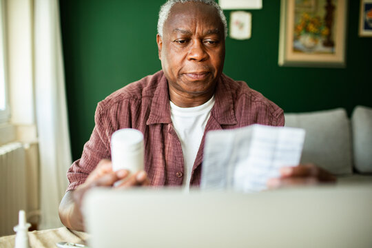 Senior man reading prescription leaflet at home