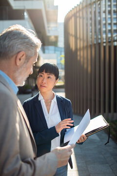 Businesswoman explaining documents to colleague outdoors