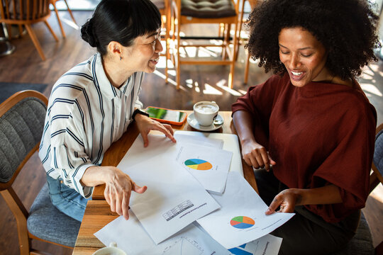 Two businesswomen discussing charts at a coffee shop