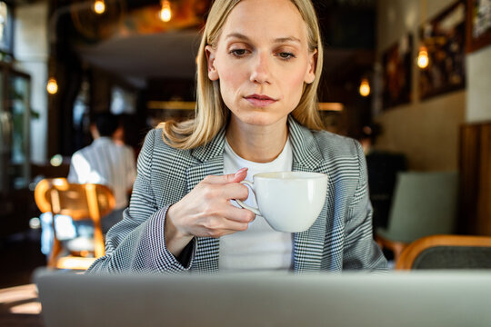 Businesswoman working on laptop with coffee in cafe