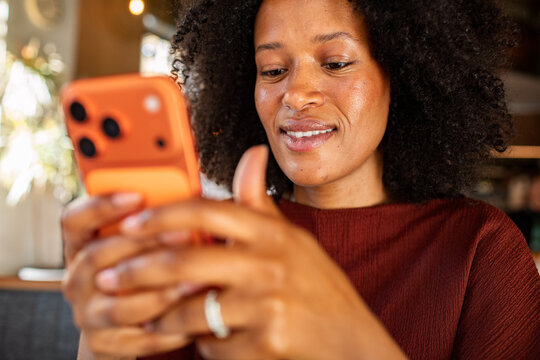 Smiling woman texting on smartphone indoors
