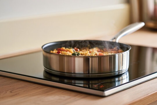 A shiny stainless steel frying pan captures a flavorful pasta dish in progress, evoking home-cooked warmth and modern culinary techniques with every bubbling ingredient.
