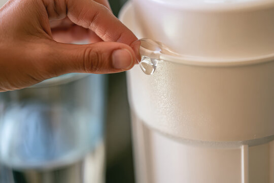A close-up image of a hand operating a water filter pitcher lid, emphasizing the importance of hydration and clean water sources for health and well-being in everyday life.