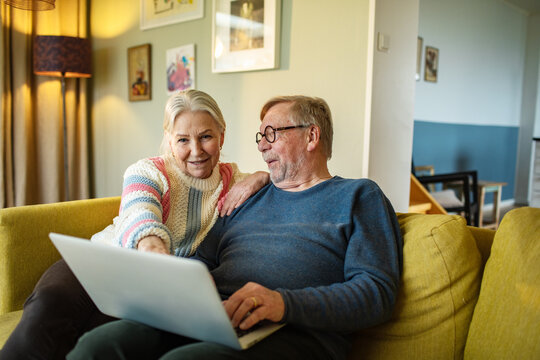 Senior woman pointing at laptop with partner at home
