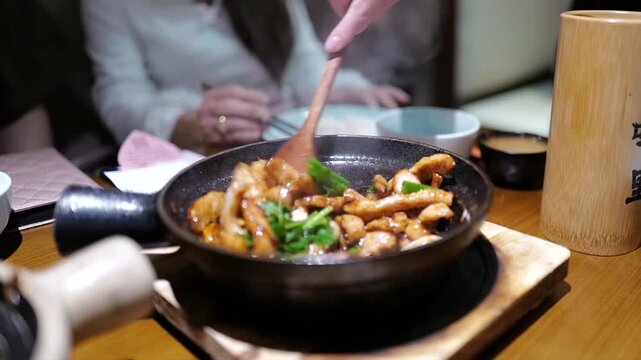 A clay pot dish filled with braised chicken, garlic, onions, green onions, and herbs, all seasoned with a savory sauce in Sanya, Hainan, China