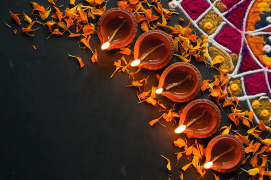 Diwali clay oil lamps with marigold petals on dark background
