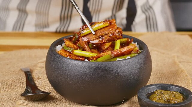 Suanmiao Huiguorou - Chopsticks picking up a juicy piece of twice-cooked pork and garlic sprouts. Real-time Asian culinary footage showing glistening pork belly and fresh greens lifted from a dish.