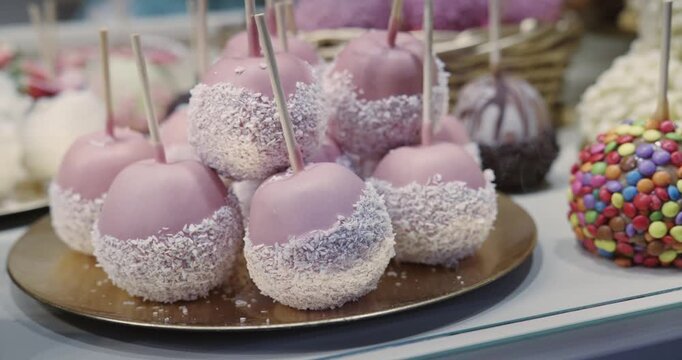 A display of decorated candied apples assorted desserts, including a chocolate covered strawberry, a chocolate covered apple at Christmas market