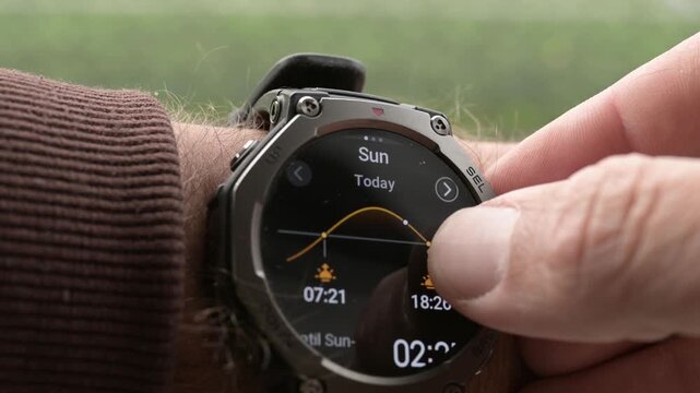Close-up of rugged smartwatch on wrist showing sunrise and sunset times today