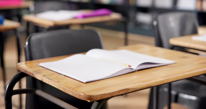 Education, notebook and desk in college for learning, study material or research in empty classroom. Stationery, campus or table in school for growth, development or scholarship opportunity in lesson