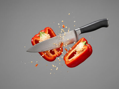 Sharp Kitchen Knife Slicing Fresh Red Bell Pepper In Midair