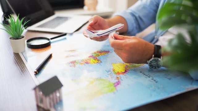 Man holding a miniature airplane above a world map, representing international relocation, immigration, moving abroad, global travel, and planning a new life in another country.