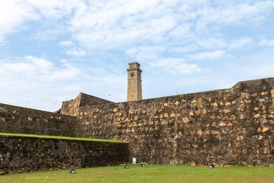 Stone fort walls and old clock tower under a blue sky with clouds, Southern Province, Galle, Sri Lanka