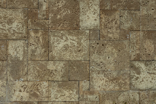 Rough Limestone Block Wall Texture Background &mdash; irregular ashlar pattern of porous pitted stone blocks with mortar joints, rustic masonry surface in cream and gray-brown tones