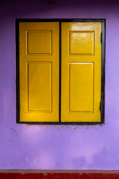 Yellow wooden window shutters on a purple wall, Northern Province, Mannar, Sri Lanka