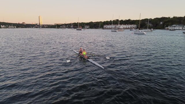 Wide aerial view of rowing athletes on Halifax Harbour, Nova Scotia, as single and double racing boats travel across the water under warm sunrise light.