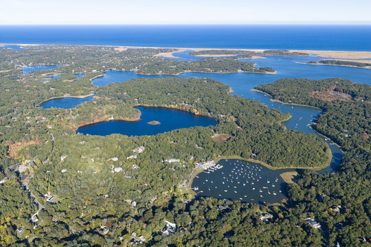A bird's eye view of Orleans on outer Cape Cod shows kettle ponds and Pleasant Bay which is connected to the Atlantic Ocean. This scenic area is a popular east coast vacation destination.