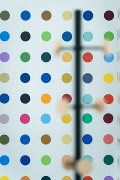 View of a wall covered in colorful polka dots, with a blurred coat rack in the foreground, in London, United Kingdom.