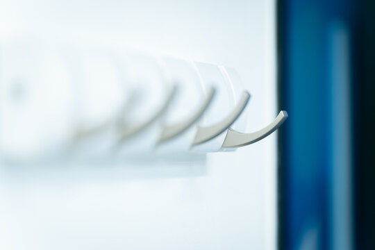 View of modern white and metallic wall-mounted coat hooks in a minimalist interior in London, United Kingdom.
