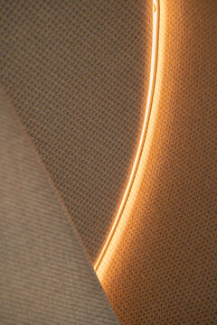 View of a textured wall panel illuminated by a curved LED light strip in an office interior in London, United Kingdom.