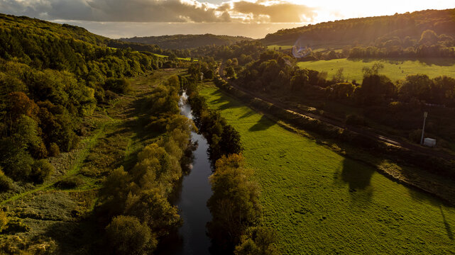 Golden sunset illuminates a river winding through a rural valley.