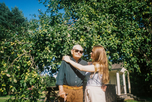 Senior Man With His Daughter Stands Under an Apple Tree