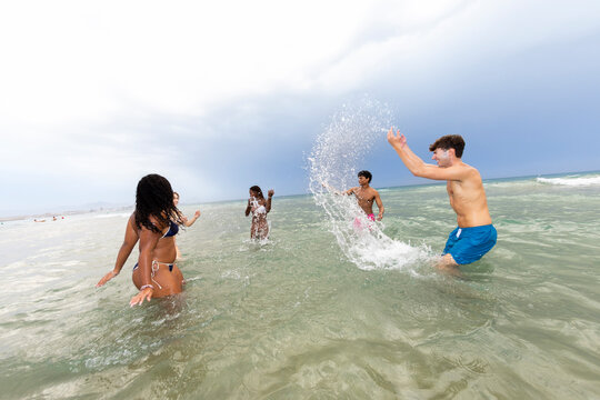 Group of friends splashing water in the beach