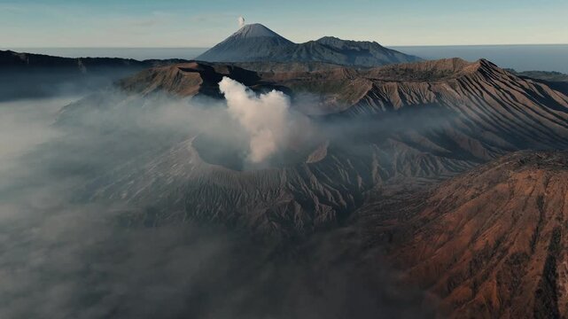 Tosari, East Java, Indonesia - 02 August 2026: Aerial view of Mount Bromo emitting smoke with volcanic craters and surrounding mist.