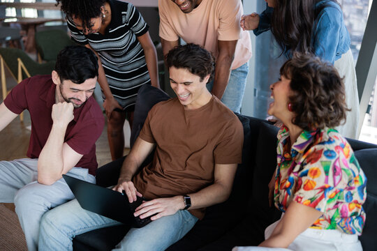 A diverse team shares a joke while collaborating
