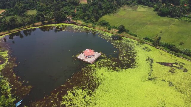Aerial drone video of Varanga Kere Basadi, a historic Jain temple on a lake surrounded by lush greenery in Varanga, Udupi district, Karnataka, India.