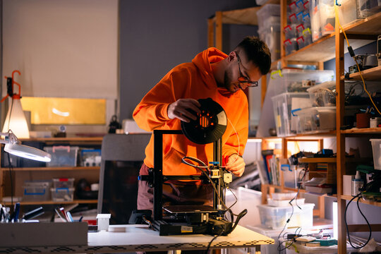 Young Man Operating 3D Printer In Workshop