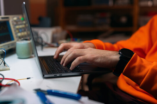 Hacker Typing On Laptop In Electronics Workshop