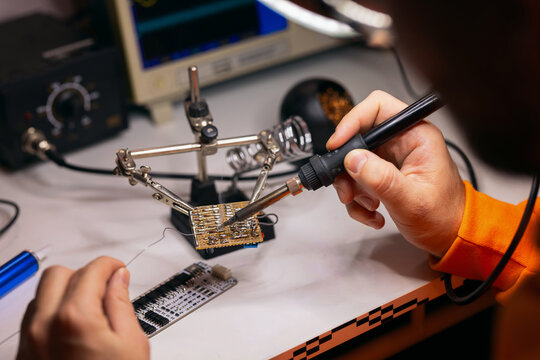 Hands Soldering Electronic Circuit Board With Helping Hands