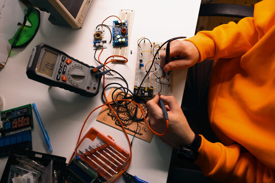 Electronics Hobbyist Testing Circuit on Breadboard With Multimeter