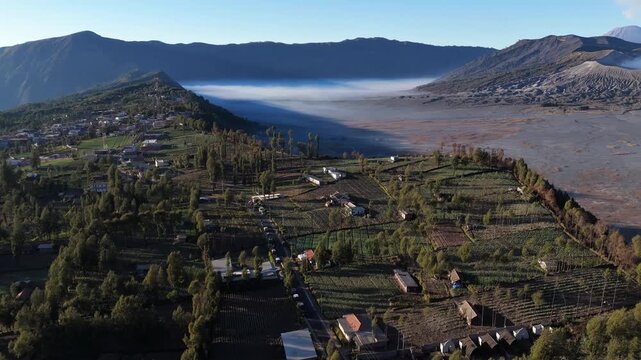 Ngadisari, East Java, Indonesia - 13 September 2026: Aerial view of Mount Bromo and the surrounding village landscape with volcanic plains and morning mist.