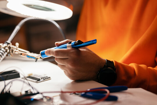 Hands Soldering Electronics on Circuit Board at Workbench