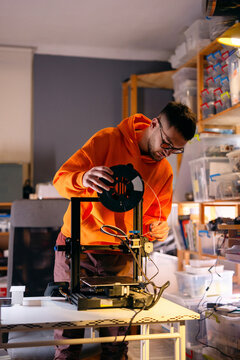 Young Man Setting Up 3D Printer With Filament Spool
