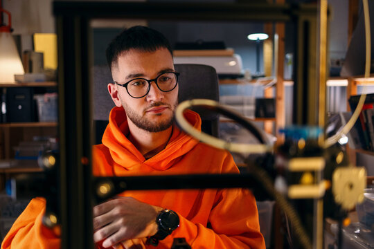 Young Man Working With 3D Printer In Workshop