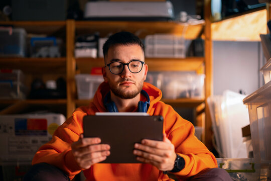 Young Man Focused on Tablet in Storage Workspace
