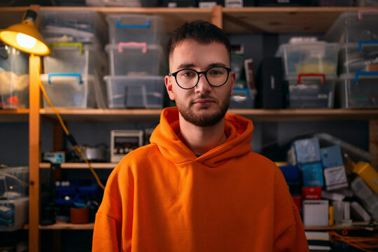 Young Man in Orange Hoodie in Workshop