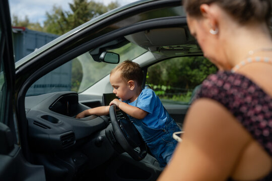 Toddler exploring car dashboard with mother