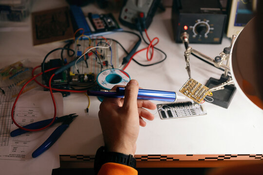 Electronics Hobbyist Soldering Circuit Board at Workbench