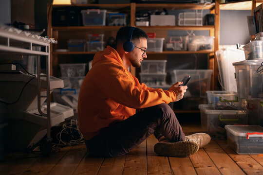 Young Man Using Phone in Electronics Workshop