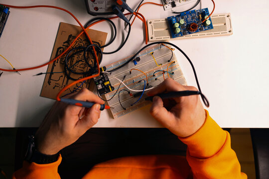 Hands Testing Electronic Circuit on Breadboard Prototype