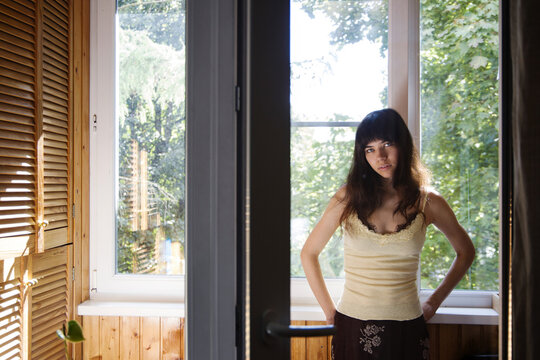 Woman standing by a window with natural light in a wooden room