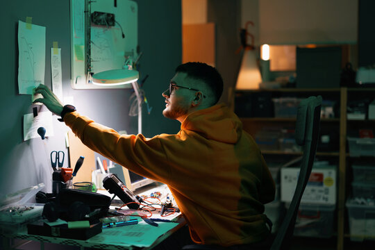 Focused Young Engineer Working on Electronics at Night