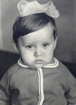 A solemn baby in a sailor suit with a bow, 1969