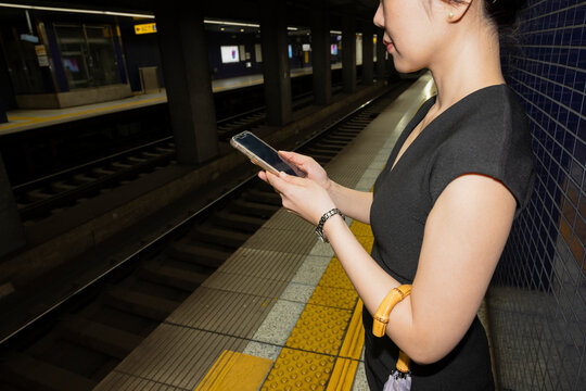 Woman Using Smartphone on Train Platform