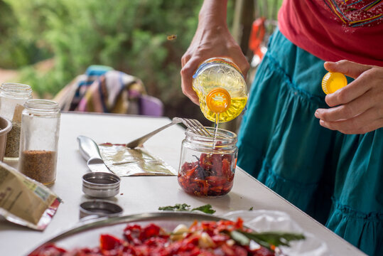 Faceless woman is preserving sun-dried tomatoes for the winter.
